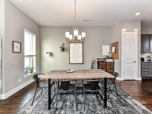 dining space featuring dark hardwood / wood-style flooring and an inviting chandelier