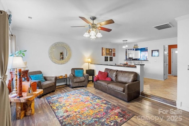 living room featuring ceiling fan, wood-type flooring, and ornamental molding