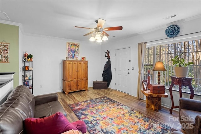 living room with light hardwood / wood-style floors, ceiling fan, and crown molding