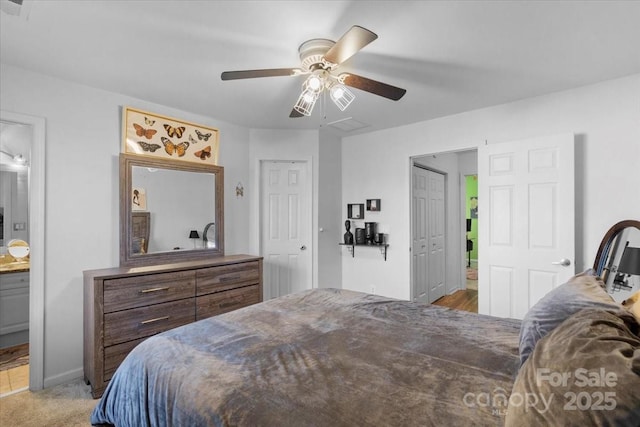 carpeted bedroom with ceiling fan and ensuite bath