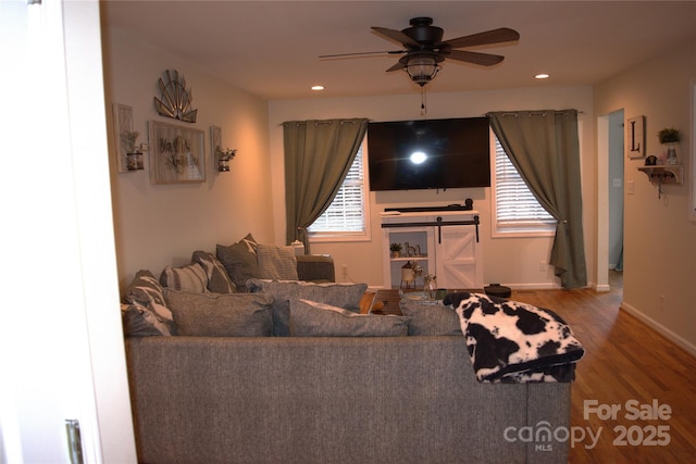 living room featuring ceiling fan, a barn door, and wood-type flooring