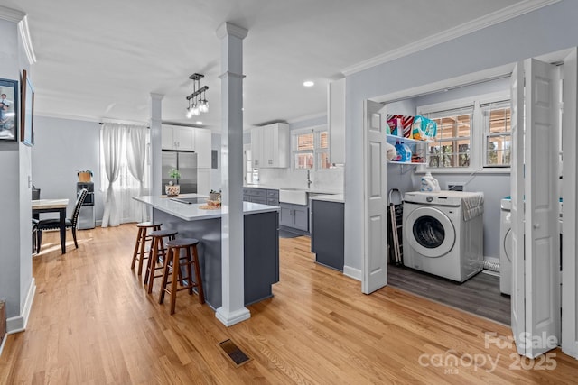 kitchen with hanging light fixtures, washer / clothes dryer, stainless steel fridge, gray cabinets, and a breakfast bar