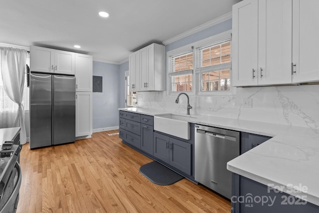 kitchen featuring white cabinetry, sink, decorative backsplash, appliances with stainless steel finishes, and ornamental molding