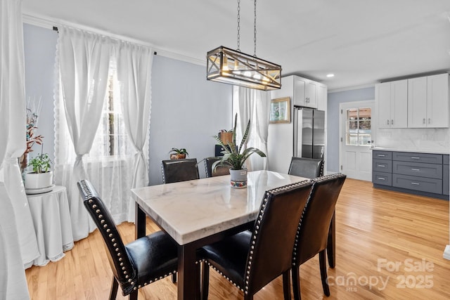 dining area with crown molding and light wood-type flooring