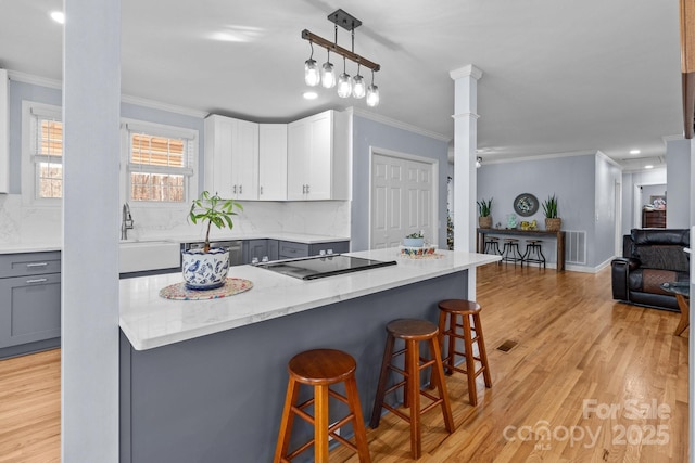 kitchen with a kitchen bar, gray cabinetry, black electric cooktop, and backsplash