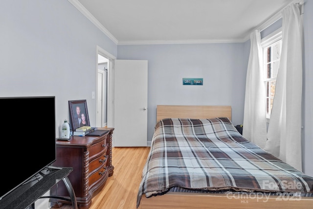 bedroom with multiple windows, light hardwood / wood-style floors, and ornamental molding