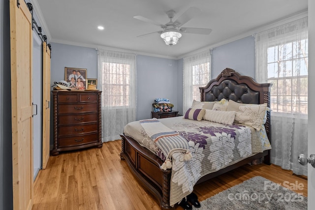 bedroom featuring light hardwood / wood-style floors, ceiling fan, a barn door, and ornamental molding