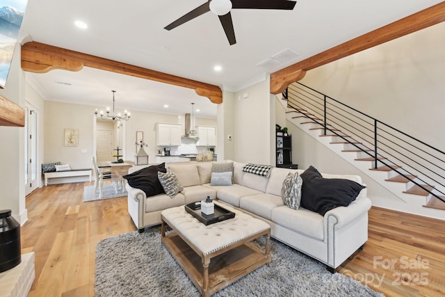 living room featuring light wood-type flooring, crown molding, and ceiling fan with notable chandelier