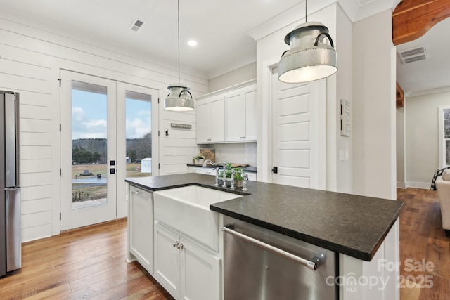 kitchen with a center island, white cabinetry, stainless steel appliances, sink, and hanging light fixtures