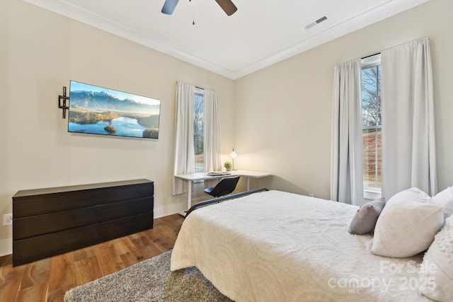 bedroom with ceiling fan, ornamental molding, hardwood / wood-style floors, and multiple windows