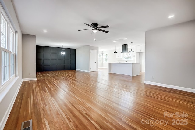 unfurnished living room with ceiling fan, sink, and light hardwood / wood-style floors