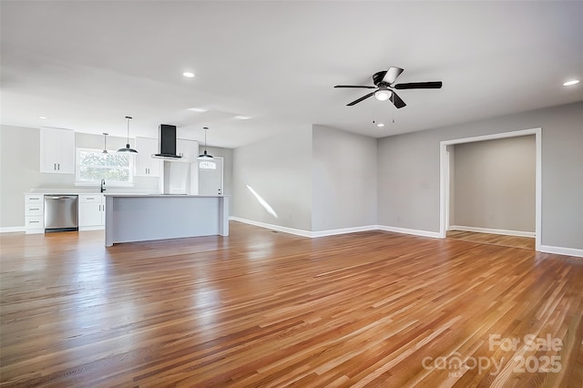 unfurnished living room featuring light hardwood / wood-style flooring, ceiling fan, and sink