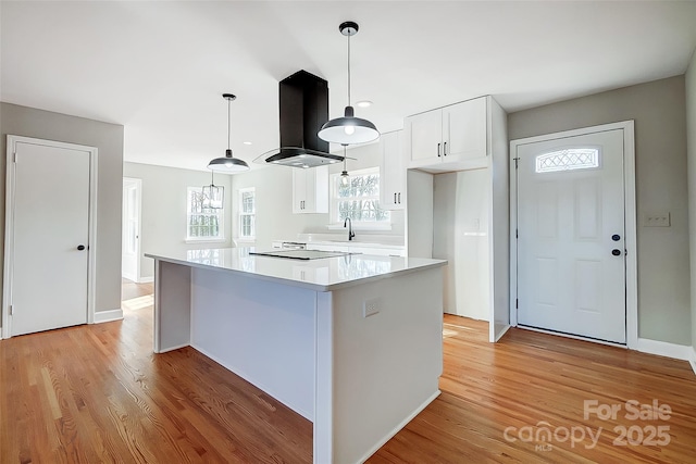 kitchen featuring white cabinetry, hanging light fixtures, island exhaust hood, light hardwood / wood-style floors, and a kitchen island