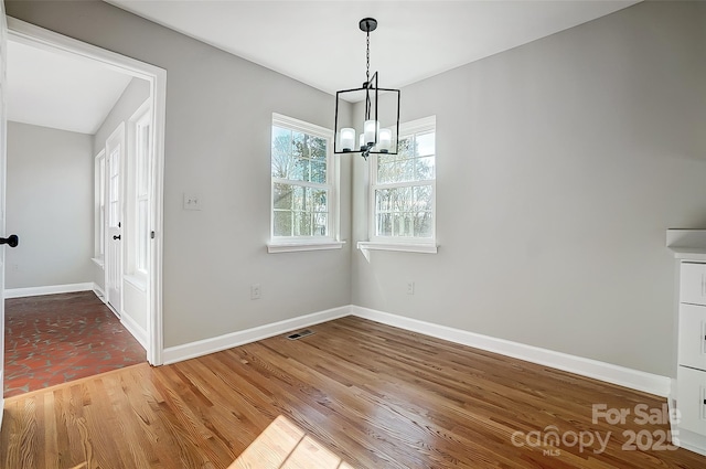 unfurnished dining area featuring hardwood / wood-style floors and a notable chandelier