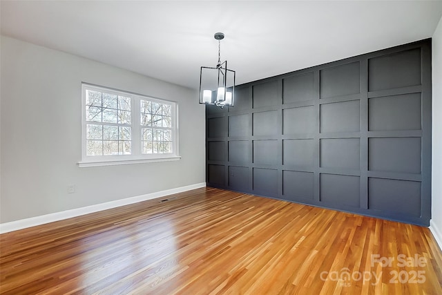 unfurnished dining area featuring a notable chandelier and light wood-type flooring