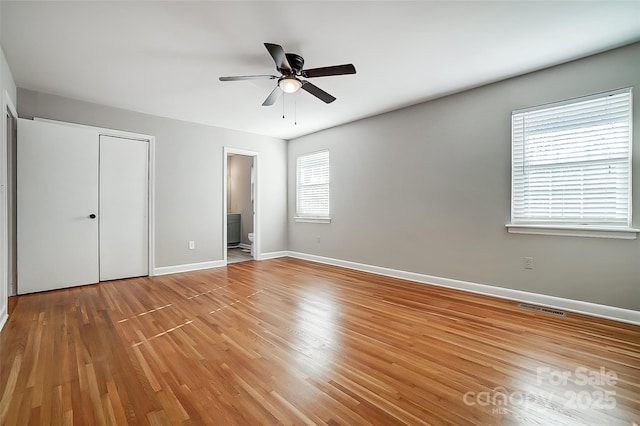 unfurnished bedroom featuring wood-type flooring, connected bathroom, and ceiling fan