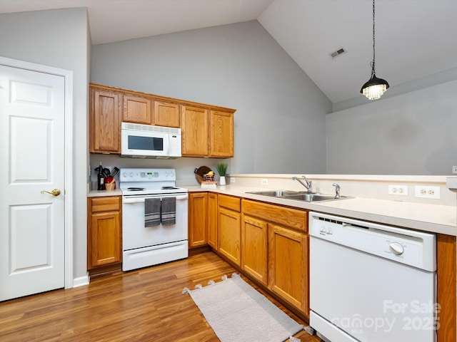 kitchen with sink, light hardwood / wood-style floors, vaulted ceiling, decorative light fixtures, and white appliances