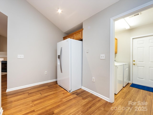 washroom with washing machine and clothes dryer, cabinets, and light wood-type flooring