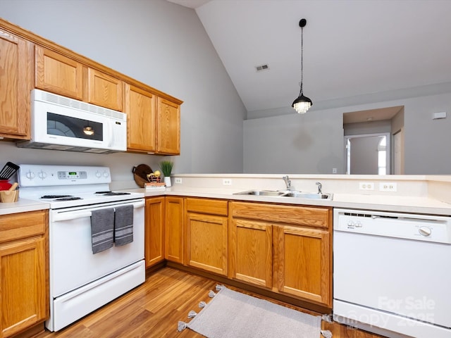 kitchen featuring white appliances, sink, light hardwood / wood-style flooring, vaulted ceiling, and decorative light fixtures