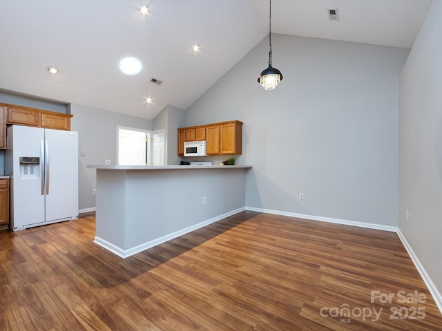 kitchen featuring kitchen peninsula, dark hardwood / wood-style flooring, white appliances, decorative light fixtures, and high vaulted ceiling