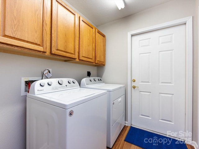 laundry area featuring cabinets, light hardwood / wood-style floors, and washing machine and dryer