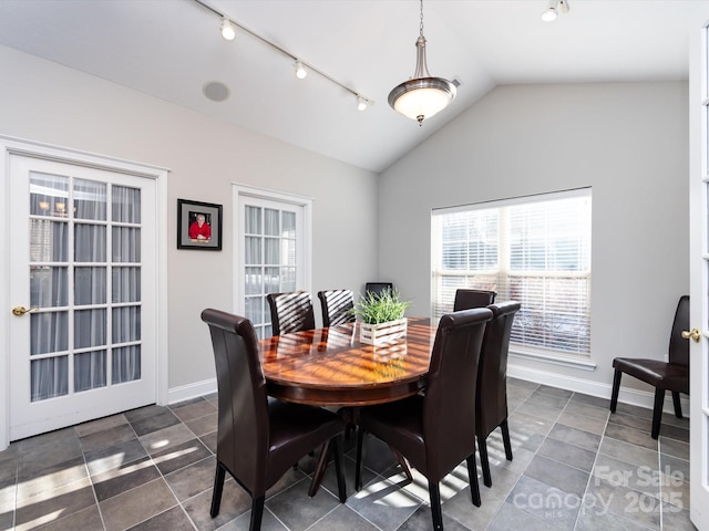 dining space featuring dark tile patterned floors and lofted ceiling