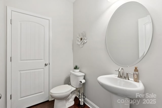 bathroom with wood-type flooring, toilet, and sink