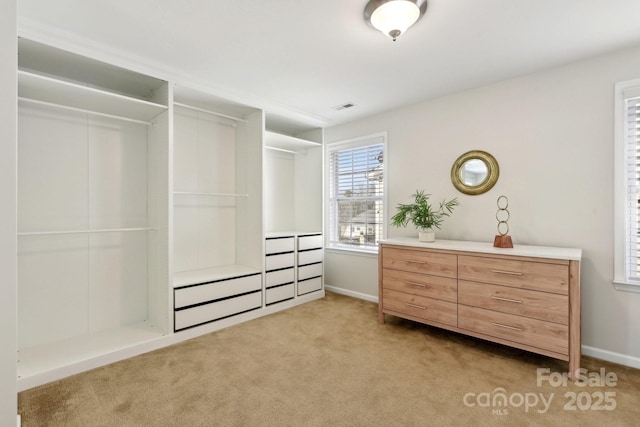 walk in closet with light carpet