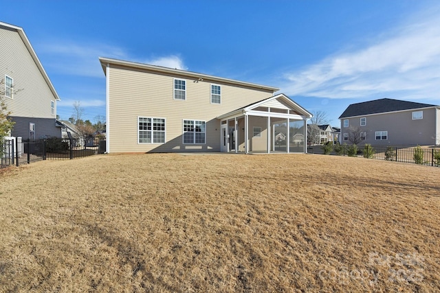 back of property with a yard and a sunroom