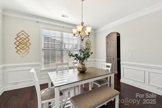 dining room with dark wood-type flooring, ornamental molding, and a chandelier