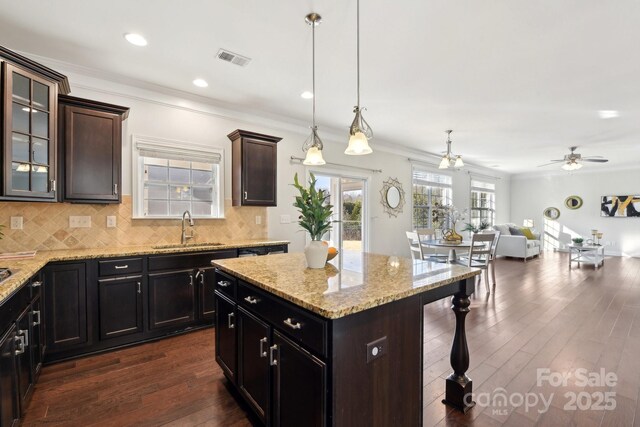 kitchen with dark wood-type flooring, sink, dark brown cabinets, hanging light fixtures, and a kitchen island