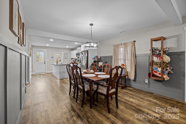 dining space featuring dark hardwood / wood-style floors, sink, and a chandelier