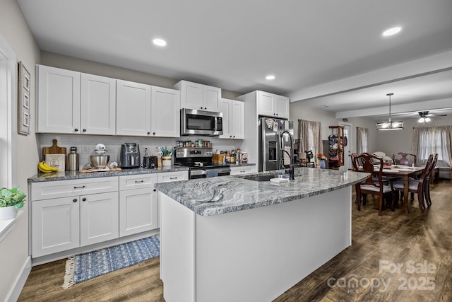 kitchen featuring a kitchen island with sink, white cabinets, hanging light fixtures, sink, and stainless steel appliances