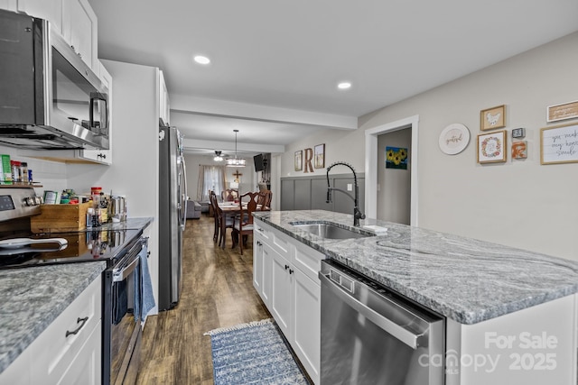 kitchen with dark hardwood / wood-style floors, light stone countertops, an island with sink, white cabinetry, and stainless steel appliances