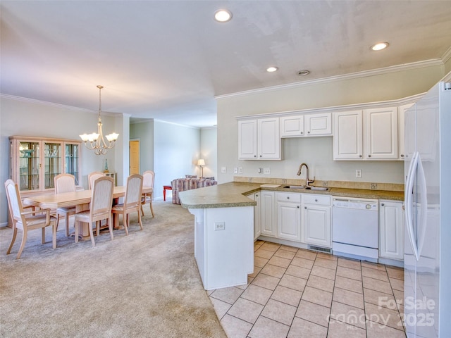 kitchen with white appliances, kitchen peninsula, sink, decorative light fixtures, and white cabinetry