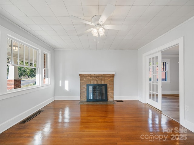 unfurnished living room with crown molding, hardwood / wood-style floors, ceiling fan, and a fireplace