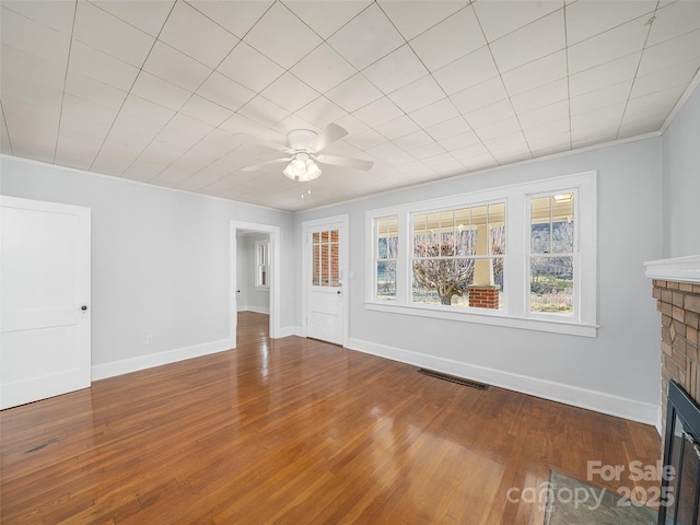 unfurnished living room with crown molding, a brick fireplace, hardwood / wood-style floors, and ceiling fan