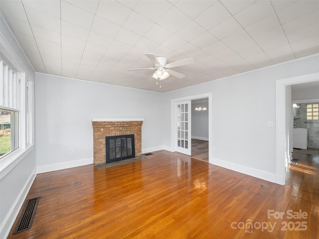 unfurnished living room with a brick fireplace, hardwood / wood-style flooring, ceiling fan with notable chandelier, and ornamental molding