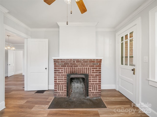 unfurnished living room featuring hardwood / wood-style flooring, ornamental molding, a fireplace, and ceiling fan with notable chandelier