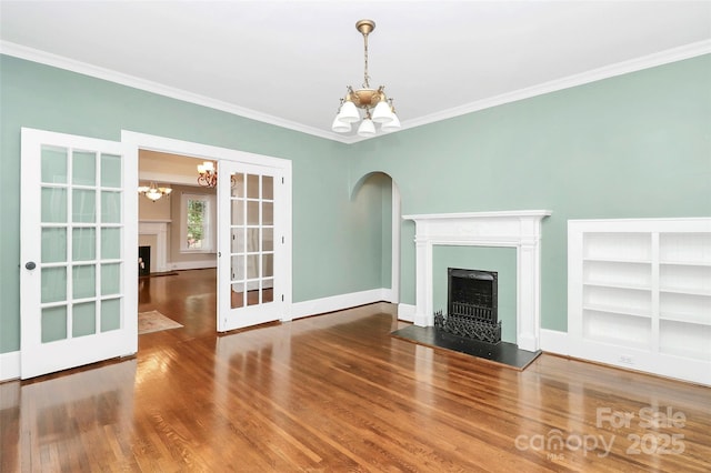 unfurnished living room featuring french doors, built in shelves, crown molding, hardwood / wood-style flooring, and a chandelier