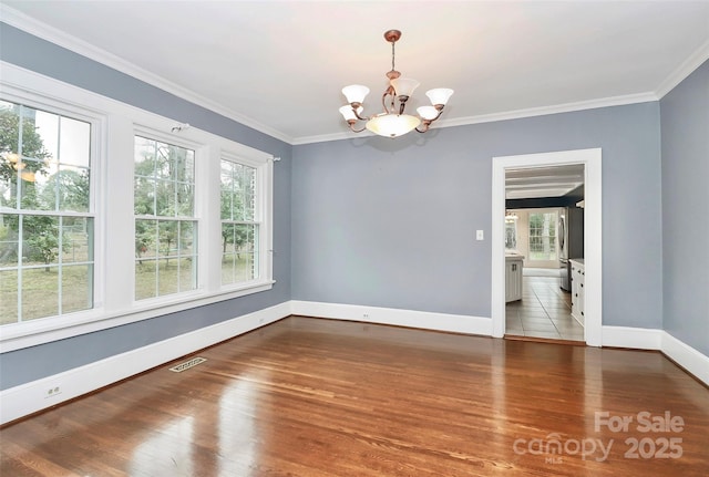 empty room featuring a notable chandelier, crown molding, and dark wood-type flooring