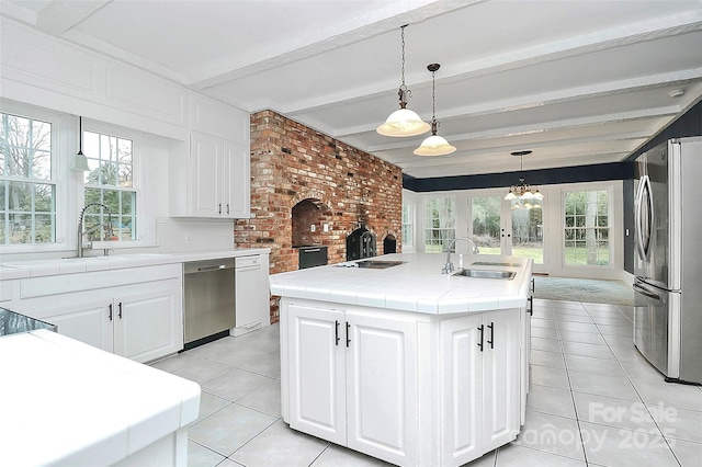 kitchen featuring white cabinets, a kitchen island with sink, appliances with stainless steel finishes, and beamed ceiling