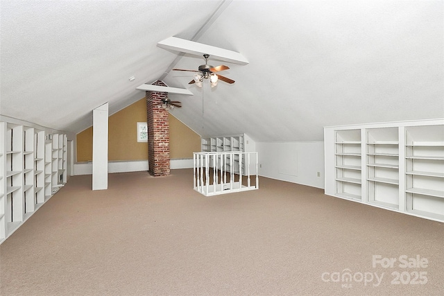 bonus room featuring lofted ceiling with beams, built in shelves, ceiling fan, a textured ceiling, and carpet floors