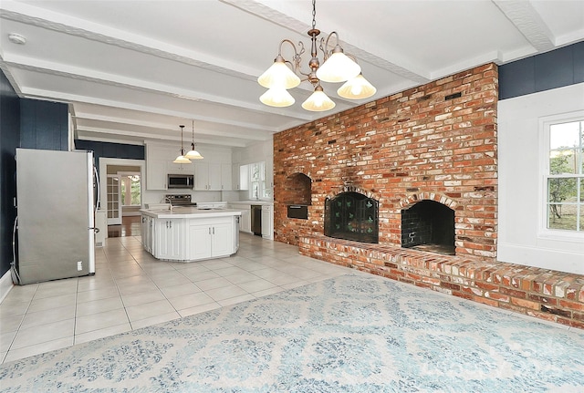 kitchen featuring a brick fireplace, beamed ceiling, decorative light fixtures, a kitchen island, and appliances with stainless steel finishes