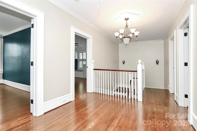 corridor featuring hardwood / wood-style flooring, ornamental molding, and an inviting chandelier