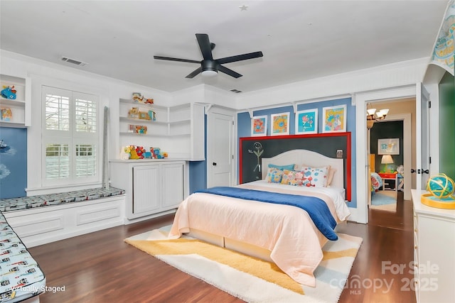 bedroom featuring ceiling fan with notable chandelier, dark hardwood / wood-style flooring, and crown molding