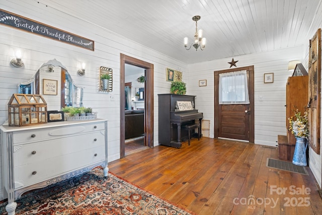 foyer featuring wooden walls, dark hardwood / wood-style floors, and an inviting chandelier