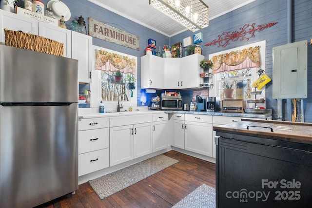 kitchen with appliances with stainless steel finishes, dark wood-type flooring, sink, white cabinets, and electric panel