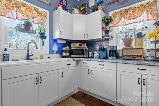 kitchen with a wealth of natural light, white cabinetry, sink, and dark hardwood / wood-style flooring