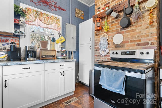 kitchen featuring electric range, brick wall, white cabinetry, and electric panel